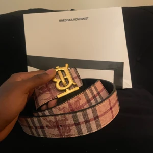  Burberry bälte med guldspänne - Säljer ett snyggt bälte från Burberry med klassiskt rutigt mönster i beige, rött och svart. Pris kan diskuteras