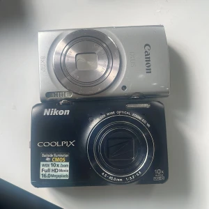 Canon IXUS 175 & Nikon Coolpix S6300 kompaktkameror - Två smidiga digitalkameror: Canon IXUS 175 med 8x optisk zoom och Nikon Coolpix S6300 med 10x optisk zoom, 16 MP och Full HD-video. Båda i gott skick med mindre ytliga repor, perfekta för resor eller vardagsfotografering. 1500 FÖR DEN SILVRIGA OCH 2500 FÖR SVARTA