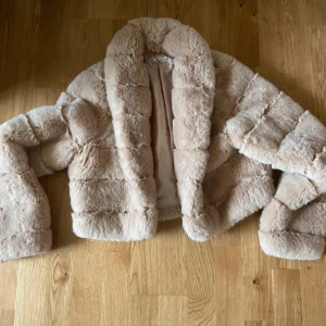 Beige pälsjacka/ kort puffer jacka - Supermjuk och fluffig beige pälsjacka med bred krage och quiltad look. Jackan är croppad och har långa ärmar samt ett glansigt innerfoder. Perfekt för dig som vill ha en cozy och trendig vibe under kyliga dagar. Från NAKD Linn Ahlborg kollektion. Väldigt lite använd.  