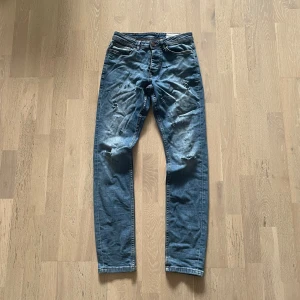 Blå jeans W28/L32 slim slitningar - Ett par najs blå jeans med storlek W28/L32 som är slim och har slitningar