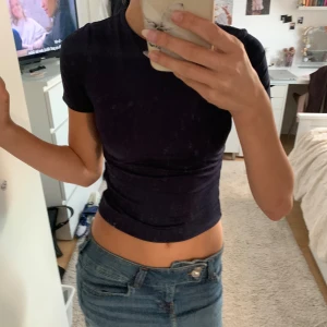 Mörkblå croppad topp med kort ärm - En enkel och stilren mörkblå croppad topp med korta ärmar och rund halsringning. Sitter tight och har en basic design som är lätt att matcha med olika outfits. Perfekt för dig som gillar en clean och minimalistisk look.
