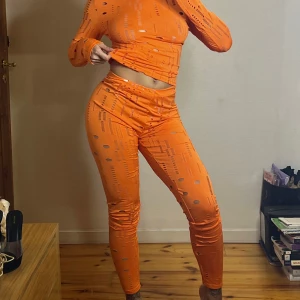 Orange leggings och tröja med hålmönster - Säljer ett par snygga orange leggings med tröja. Coola hål och mönster i tyget. De är tighta och stretchiga, sitter högt i midjan och har en modern vibe. Perfekta om du vill sticka ut och gillar färg. Materialet känns som syntet och de är superbekväma. Använda 1 gång.