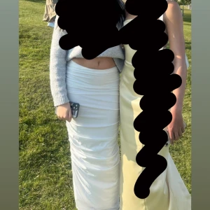 Vit långkjol med rynkade detaljer - Säljer en snygg vit långkjol med rynkade detaljer längs hela kjolen. Kjolen har en tight passform och är perfekt för dig som vill ha en stilren och trendig look. Materialet känns mjukt och följsamt mot kroppen. Storlek är i XS men skulle nog passa i S oxå, den är andvönd en gång på en bal inga fläckar eller något.