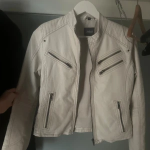 Vit skinnjacka från Livelo, stl 38 - Snygg vit skinn/läderjacka från Livelo med coola detaljer som flera dragkedjor framtill och på ärmarna. 
