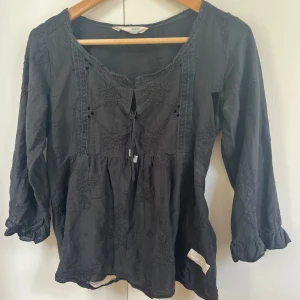 Svart broderad blus med knyt  - Svart blus från Odd Molly med broderade blommor och knytning framtill. Mycket hål som ni ser men annars jättefin!! Så om du gillar och sy och vill ha ett projekt här finns ett😅 säljs pga av att jag inte orkar sy/kan knte sy. Väldigt träkigt för det ör en väldigt fintröja som jag tyckt mycket om.❣️❣️😢