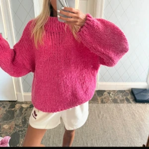Oversized rosa stickad tröja - Supermysig oversized stickad tröja i en stark rosa färg. Tröjan har grovstickat material, bred ribbad krage och långa, vida ärmar. Perfekt för dig som gillar en chill och trendig look med extra volym i ärmarna.
