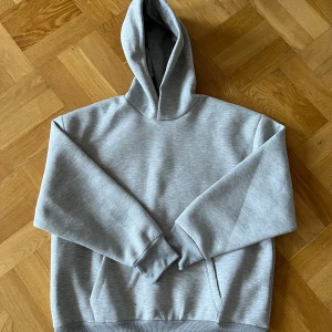 Ljusgrå basic hoodie med huva från ASOS - En stilren ljusgrå hoodie med huva och magficka. Perfekt för dig som gillar en enkel och clean look. Nyskick aldrig använd