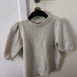 Beige stickad tröja från Vero Moda - Superfin beige stickad tröja från Vero Moda med kort puffärm.