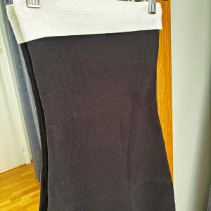 Svart klänning med vit resår från Bikbok - Säljer en klänning från Bikbok med bred, vit resår ovantill. Bandeauklänningn är ribbad och har en stilren, figurnära passform. Perfekt för dig som gillar minimalistisk och clean stil. Materialet är mjukt och stretchigt för extra komfort.