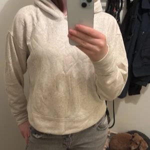Beige hoodie från Old Navy - Mysig beige hoodie från Old Navy i storlek S. Tröjan har en luva, långa ärmar och är tillverkad i mjukt material med små svarta prickar. Perfekt för chill dagar och enkel att matcha med jeans eller mjukisbyxor. har en liten fläck i mitten pp magen men den går bort i tvätten(kan tvätta innan jag skickar) och jag såg den bara när jag lyste med ficklampa över hela tröjan.