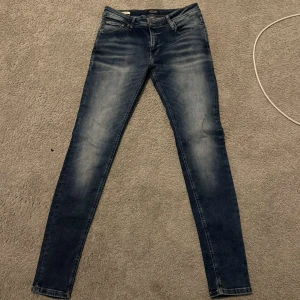 Blå slim fit jeans från Jack & Jones - Snygga blå skinny jeans från Jack & Jones med slitningar och tvättade, strl 32-34