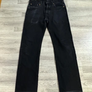 Svarta Levis 501 straight jeans - Svarta Levis 501 jeans med klassisk rak passform och femficksdesign. Jeansen har knappgylf och är tillverkade i robust denim. Perfekta för dig som gillar en tidlös och clean look. Storlek W33/L36