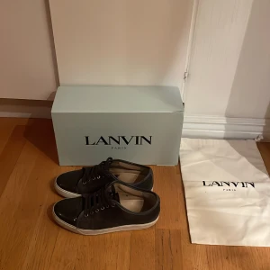Svarta sneakers från Lanvin - Snygga svarta sneakers från Lanvin med vit sula och klassisk snörning. Skorna är i bra skick men har gått sönder lite vid sulorna. Storleken är 41 men passar även 42. Pris kan diskuteras.
