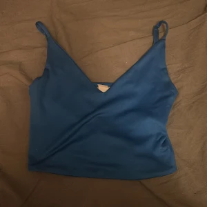 Blå linnetopp från Amisu XXS - Säljer en stilren blå linnetopp från Amisu i storlek XXS. Toppen har smala axelband och v-ringning framtill, vilket ger en enkel men snygg look. Tillverkad i mjuk och stretchig polyesterblandning som sitter skönt på kroppen.