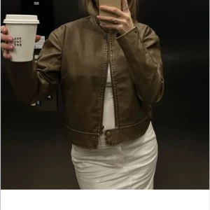 Brun vintage jacka - Snygg brun skinnjacka i kort modell. Använt några gånger då jackan sitter tajt. Köpt för 500kr på rea. Jackan har ett litet hål inuti fickan men inga defekter utöver hålet.