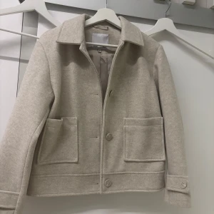 Beige ulljacka - Stilren beige jacka från 157 med klassisk krage, stora fickor framtill. Är i strl 160 men passar mig som bär XS / S i kläder.  Skickar gärna  mer bilder om du är intresserad! Vid snabb affär kan jag gå ner i pris! 