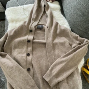 Beige kofta med huva från Less Worries - Säljer nu denna kofta från less worries, använd nästan aldrig så den är som helt ny, ny pris 1799 kr, storlek S men passar även M