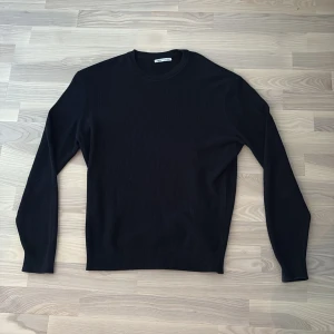Tröja - Zara - Navy blå stickad tröja från Zara i storlek M. Tröjan har rund halsringning och ribbade muddar vid halsen, ärmslut och nederkant. Enkel och stilren design med långärmade ärmar, perfekt för lager-på-lager under kyliga dagar.