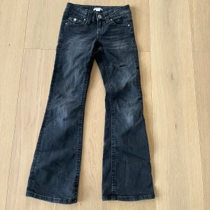 Svarta Low waist bootcut jeans - Snygga svarta jeans low waist bootcut  och coola fickdetaljer med knappar både fram och bak.