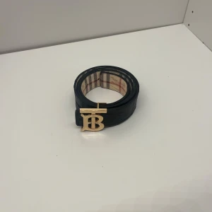 Burberry bälte - Ett reverseble burberry bälte så man kan byta sida på bältet så man har både svart och beige bälte med guldigt logga och den är helt ny och den är i 105 cm. Pris kan diskuteras och skriv om du har några frågor. 