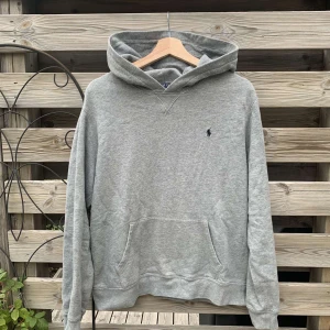 Grå Ralph Lauren Hoodie - Snygg grå Ralph Lauren Hoodie i storlek XL (18-20), passar XS eller S i vuxenstorlek (se mått nedan). Använd men i fint skick. Hör gärna av er vid minsta fundering🙌   Längd från axel och ner: 59-60 cm Bredd under armhålorna: 51-52 cm  Vänligen notera att mått kan skilja 1-2 cm. Jag mäter alltid så noggrant som möjligt.