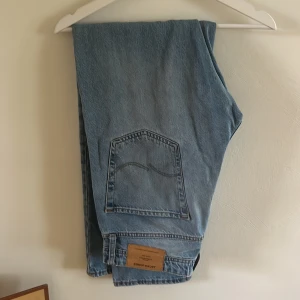 Jack & Jones Loose Fit Ljusblå Jeans - Ljusblå jeans från Jack & Jones i loose fit-modell, modellnamn Chris. Klassisk femficksdesign med stora bakfickor och snygga kontrastsömmar. Tillverkade i slitstarkt bomullsjeansmaterial, perfekta för en avslappnad och trendig look.