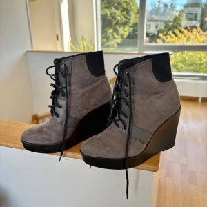 Gråa kilklacksboots från Zara - Snygga grå boots från Zara med kilklack och snörning framtill. Ovandel i mocka och detaljer i svart textil och skinnimitation. Se skicket på bilderna 💕