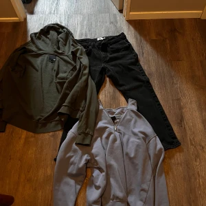 Olivgrön hoodie från 157 och svarta jeans men även en blå half zip från H&M - Två snygga tröjor: en olivgrön hoodie från 157 med huva och mjukt material, samt en grå sweatshirt från H&M med half zip-dragkedja och relaxed fit. Perfekta för lager-på-lager och chill dagar. Båda har långa ärmar och klassisk stil.