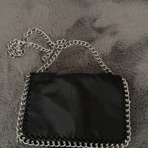 Svart axelväska med kedja från Tiamo - svart axelväska från märket Tiamo, nypris 500 , använts en del men är fortfarande fin