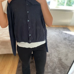 Mörkblå kofta från 157, storlek S - Mörkblå kofta från 157 i storlek S. Klassisk modell med rund halsringning, ribbade muddar och knäppning framtill med blå knappar. Tunn och mjuk, perfekt att slänga över en t-shirt. Enkel och stilren design som funkar till det mesta.