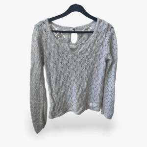 Ljusgrå stickad tröja Odd Molly - Supersöt ljusgrå stickad tröja från Odd Molly i 100% bomull. Tröjan har ett vackert hålmönster, rund halsringning och lång ärm. Fin detalj med knapp och öppning i nacken. Perfekt för lager-på-lager och en chill men ändå stilsäker look.