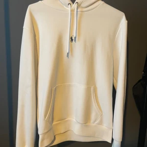 Vit hoodie från Polo Ralph Lauren - Säljer en stilren vit hoodie från Polo Ralph Lauren med klassisk broderad logga på bröstet. Tröjan är nästan helt oanvänd. Vänlig och kontakta om du har fler frågor.