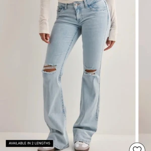 Ljusblå bootcut jeans med hål - Snygga ljusblå jeans med bootcut passform och slitna hål över knäna. Jeansen har klassisk femficksdesign, broderad detalj på bakfickorna och är tillverkade i mjukt denim. Perfekta för dig som gillar en avslappnad och trendig look.