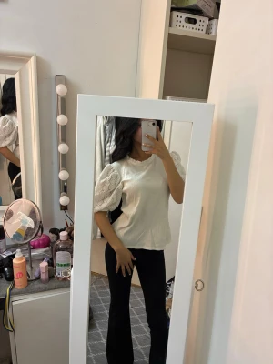 Vit blus med puffärmar och spets - Säljer en vit blus med ribbad struktur och puffiga spetsärmar. Blusen har rund hals med liten volangkant och är tillverkad i mjukt material. 