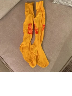 Sportstrumpor  - Bilden visar ett par gula sportstrumpor med röd text,  43-45