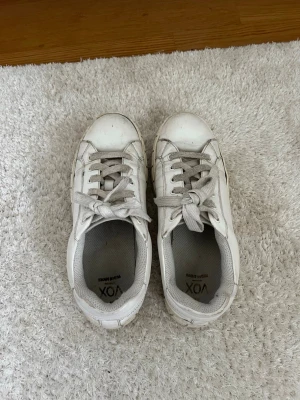 Vita sneakers från VOX med platåsula - Säljer ett par vita sneakers från VOX med chunky platåsula och snörning. Skorna har rund tå och är gjorda i syntetmaterial med textilfoder. Klassisk och enkel design som passar till det mesta. Storlek 39.