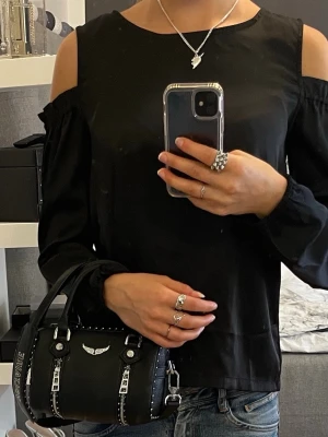 Offshulder blus - Svart off shoulder blus med långa ärmar med resår vid handlederna som ger en snygg puffeffekt. Passar XS/S.