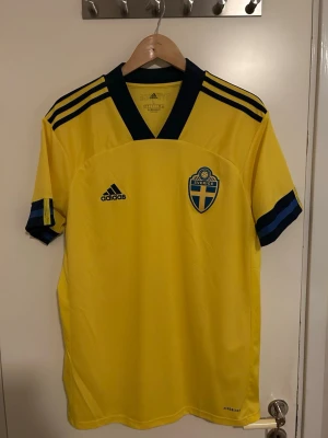 Äkta Sverige hemmatröja från säsongen 2020/21 - Säljer en äkta Sverige hemmatröja från säsongen 2020/21 i storlek L. Tröjan är i mycket bra skick och har inga skador eller fläckar. Perfekt för dig som vill visa ditt stöd för blågult på matchdagen eller samlar på landslagströjor. 