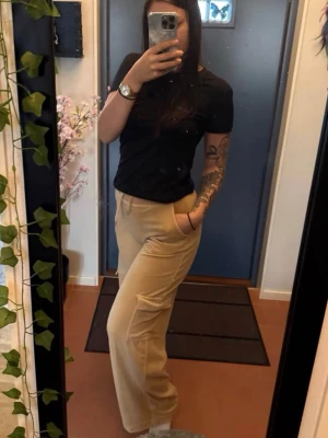 Juicy Couture - Säljer ett par beiga cargopants med breda ben och snygga fickor på sidorna. Byxorna har hög midja, dragsko i midjan och är dekorerade med strassdetaljer på rumpan. Mjukt material som känns skönt mot huden och ger en chill vibe.