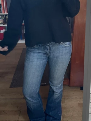 Blå bootcut jeans med broderad ficka - Snygga blå jeans med bootcut passform och klassisk femficksdesign. Jeansen har en broderad detalj på bakfickan och är tillverkade i jeansmaterial med lätt tvättad look. Midjemått 40 cm , och innerbensmått är 80 om jag minns rätt.