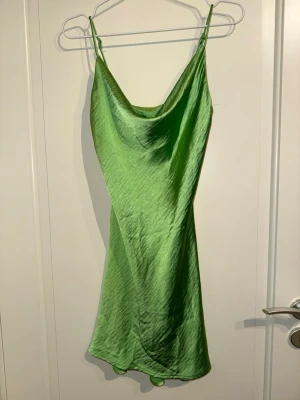 Grön satängklänning - Hyfsat kort klänning i satäng, har lite trådar men inget som syns när man har på sig den.