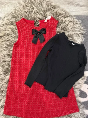 Röd ärmlös klänning med svart rosett - Säljer en svart långärmad topp med en röd kortklänning med en svart rosett framtill vid halsen.