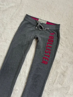 Low waist mjukisbyxor från Hollister - Så så så sjukt snygga mjukisbyxor från Hollister med rosa/röd text längs benet och snörning i midjan. Köpte dom på Plick i veckan men säljer då dom var för små🤕 pris går att diskutera!! Dom är använda, men riktigt fin vintage look, ger mjukisbyxorna mer personlighet 😆