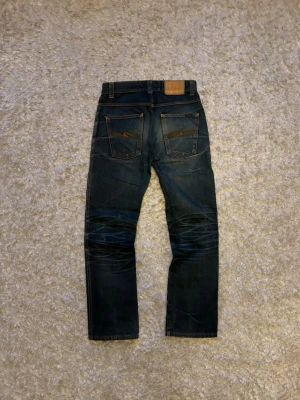 Nudie jeans low slim Jim raw vintage - Sjukt feta o eftertraktade jeans från nudie, de är välanvända vilket gett jeansen den snygga faden. Modellen är slim Jim och storleken W30 L30, men jämför med måtten nedan.   Hela längden: 101 Innerben: 77 cm Midja: 38,5 cm Benöppning: 20,5 cm