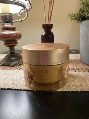 Rituals Intuita whipped body cream - Oöppnad. Lyxig whipped body cream från Rituals i serien Intuita. Kommer i en rund glasburk med guldfärgat lock och blommigt motiv på sidan. Doften är sandelträ och mandarin essence. Perfekt för dig som vill ha en återfuktande och väldoftande kroppskräm.