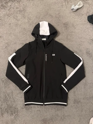 Lacoste jacka - Lacoste Vindjacka Svart med vita detaljer i NYTT SKICK, Storlek S kom privat för mer frågor