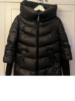 Svart pufferjacka från tatuum - Säljer en svart pufferjacka från Tatuum med hög krage och huva. I strl 34 men passar mig som är strl 36 vanligtvis💘