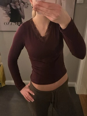 Vinröd långärmad topp Gina Tricot - Säljer en vinröd långärmad topp från Gina Tricot i storlek 158/164. Toppen har v-ringning med spetsdetaljer och är figurnära i modellen. Materialet är mjukt och stretchigt, perfekt för dig som gillar stilrena plagg med en liten twist.