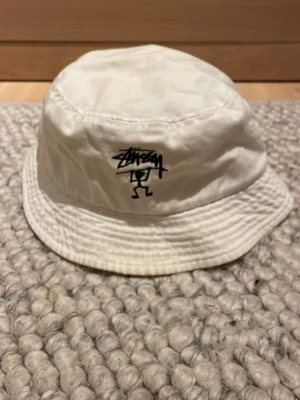 Stüssy bucket hat - Vit bucket hat från Stüssy med svart logga framtill.