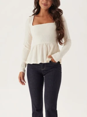 Vit blus med fyrkantig ringning - Supersöt vit blus med lång ärm och fyrkantig ringning. Blusen har en lätt rynkad struktur och volang nedtill som ger en romantisk vibe. Perfekt att styla med jeans eller kjol för en fräsch look. säljer för jag fick den i julklapp och den är jätte fin men den var för liten och mamma köpte den för tidigt så den går inte att lämna tillbaka. prislappen är kvar. 